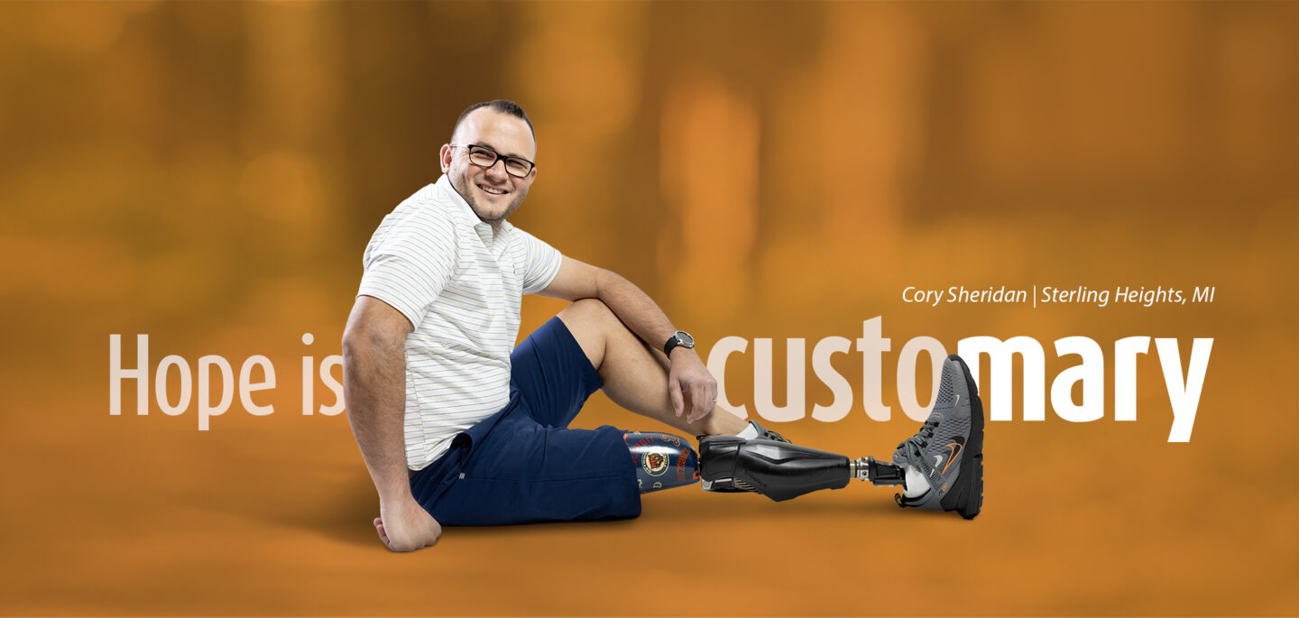 Cory Sheridan from Sterling Heights, MI, sits confidently with his custom prosthetic leg on display. The background text reads 