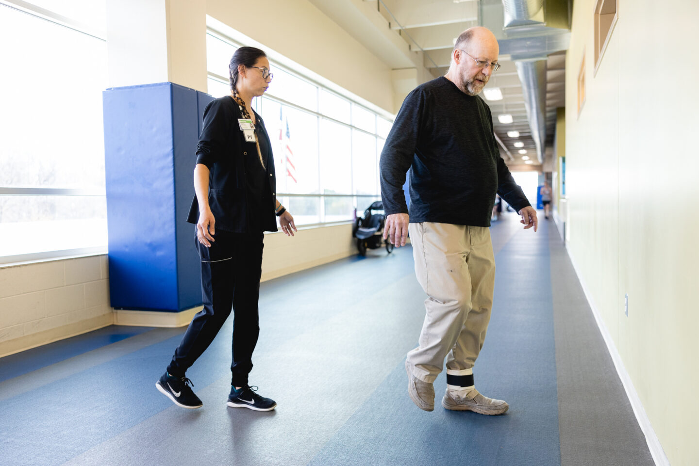 Senior patient walking with the support of a physical therapist for sports injury rehabilitation.