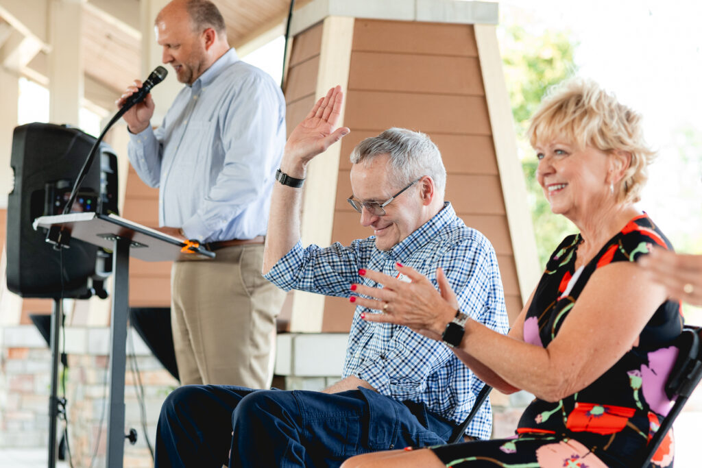 Dr. Ball laughing and raising his hand at his retirement party from Mary Free Bed