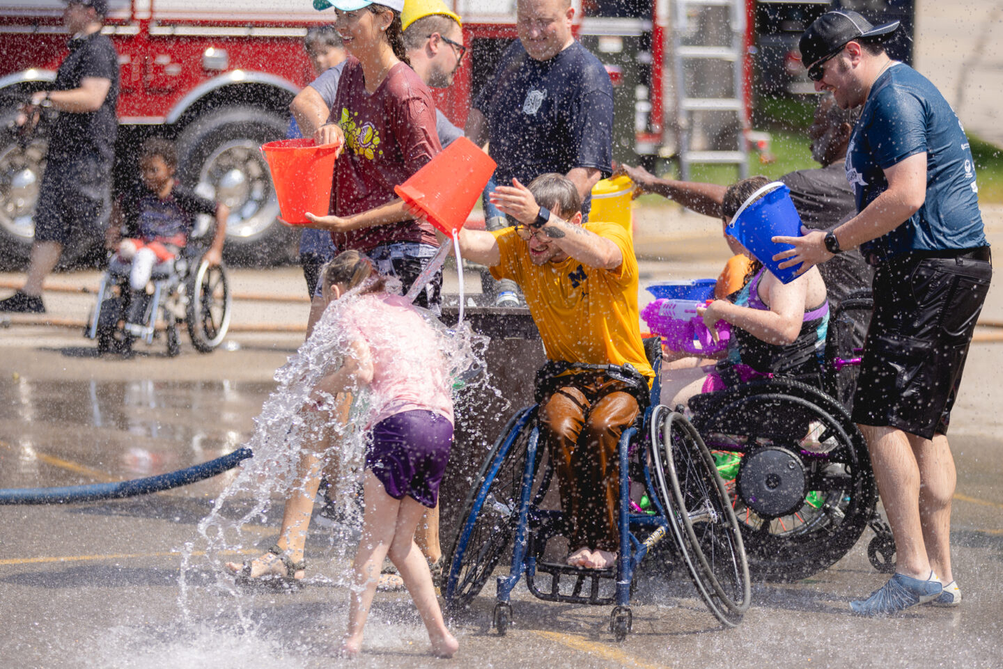 Campers enjoying a water fight with buckets and hoses with the Allendale Fire Department at Junior Wheelchair Sports Camp.