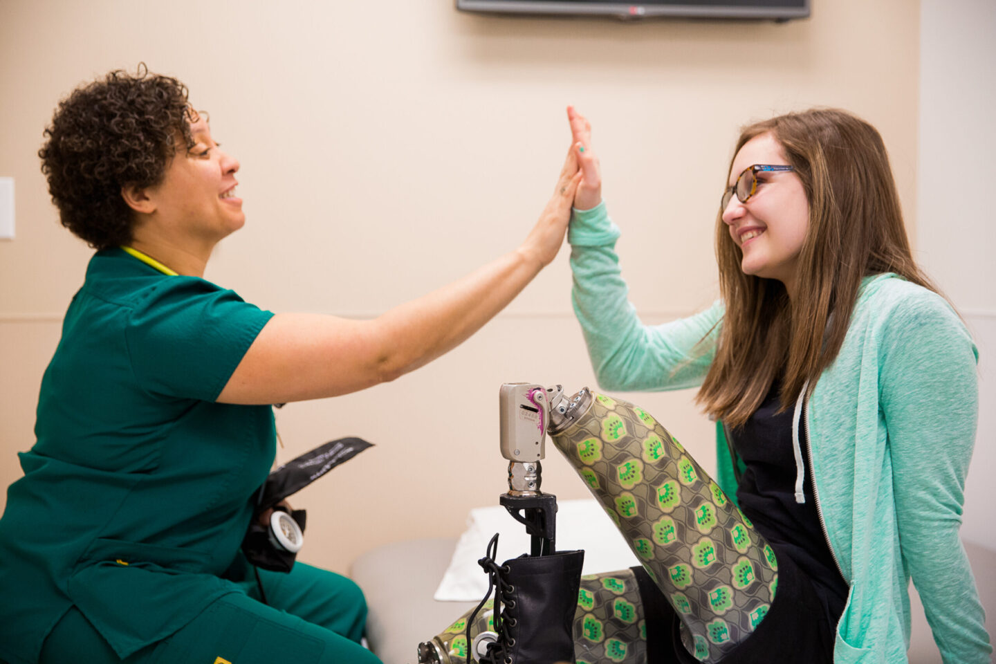 Clinician giving a high five to a young patient with a prosthetic leg.