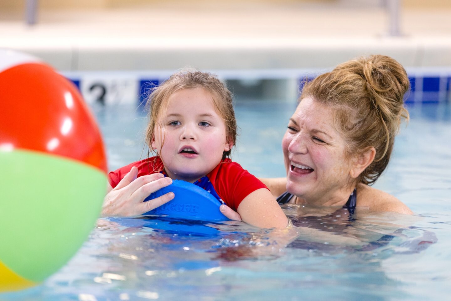 A child and a recreational therapist engage in a fun and supportive pool exercise.