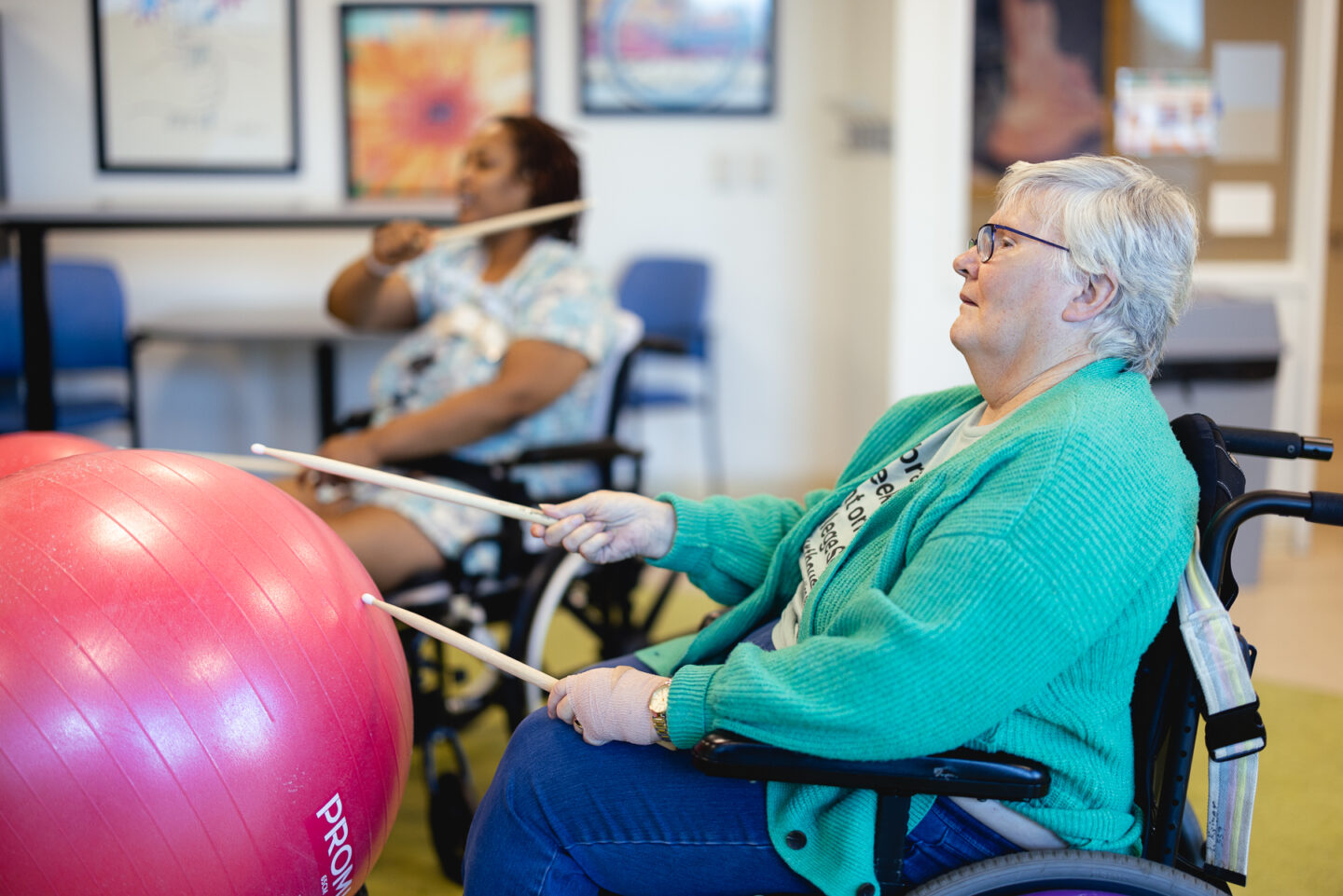 Senior patients participate in a cardio drumming session with exercise balls and drumsticks.