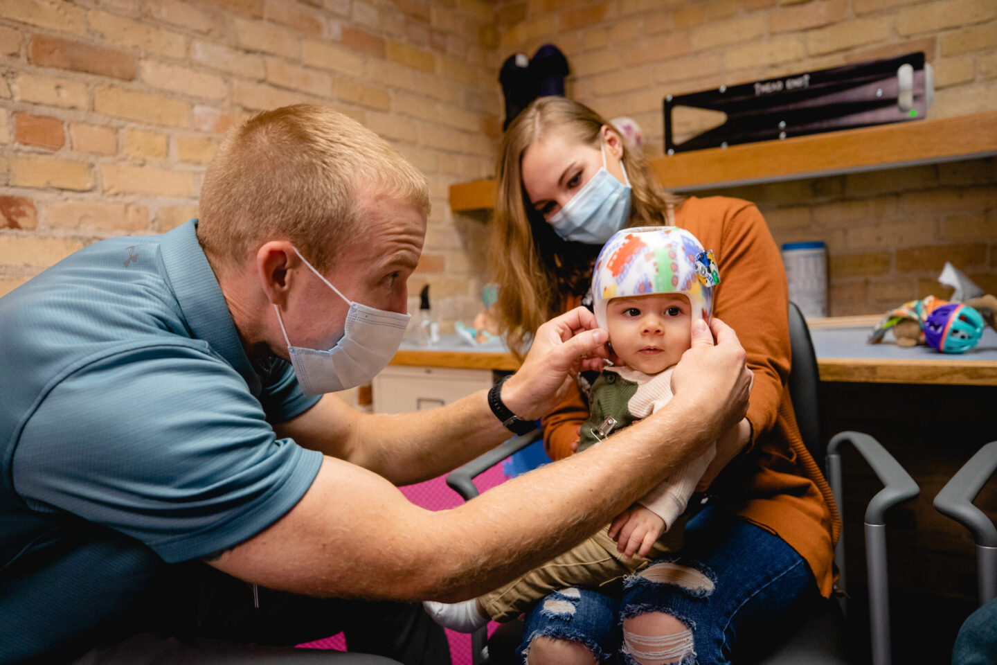Clinician fitting a baby with a cranial helmet at Mary Free Bed's orthotics and prosthetics clinic in Saginaw.