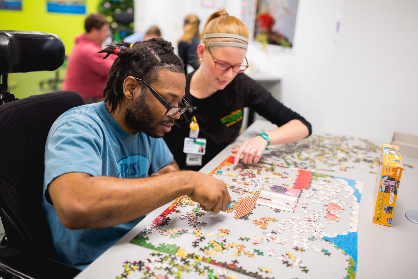 An adult man works on a large puzzle with a recreational therapist, focusing on cognitive and social skills during a therapy session.