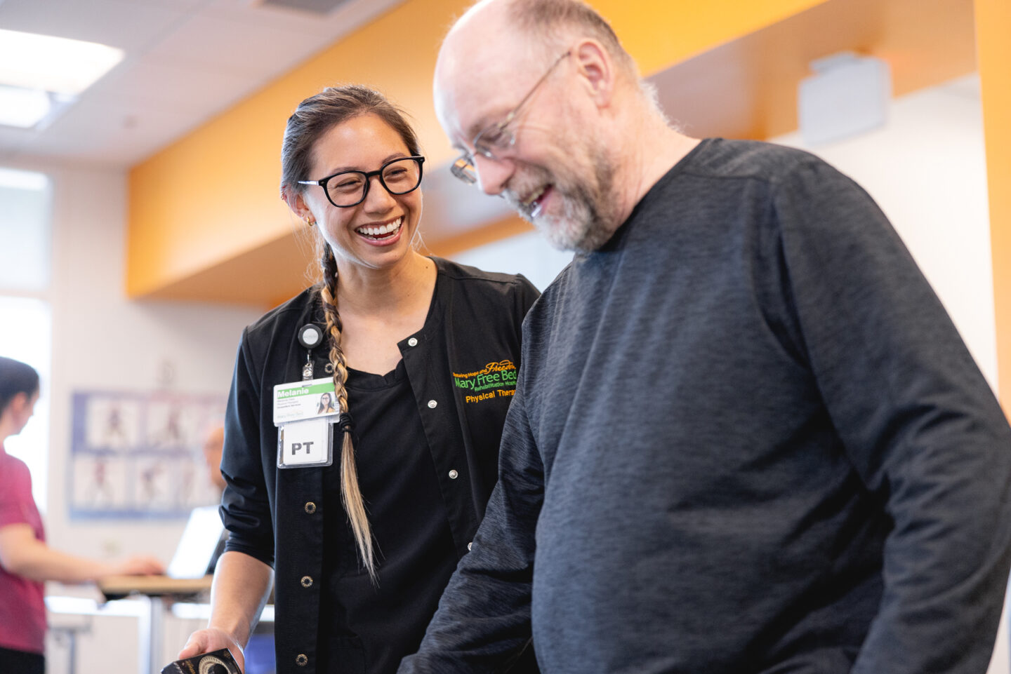 Physical therapist smiling and assisting an older adult during a fall prevention session.