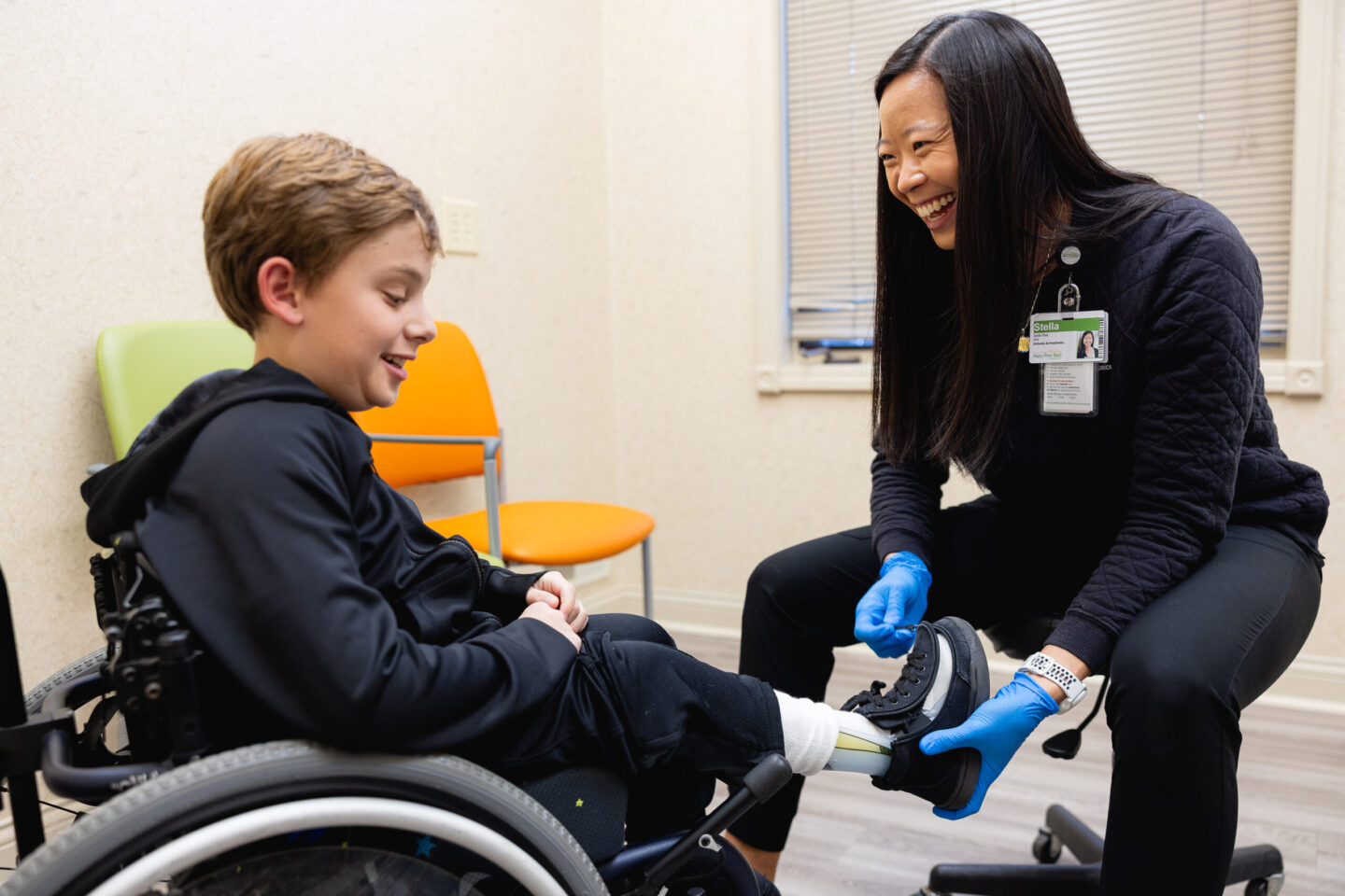 A young boy in a wheelchair laughs during his orthotics fitting.