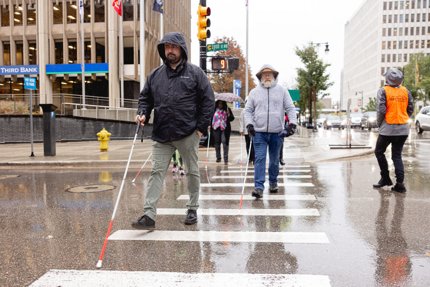 people walking through a city downtown using white canes as an accessibility tool