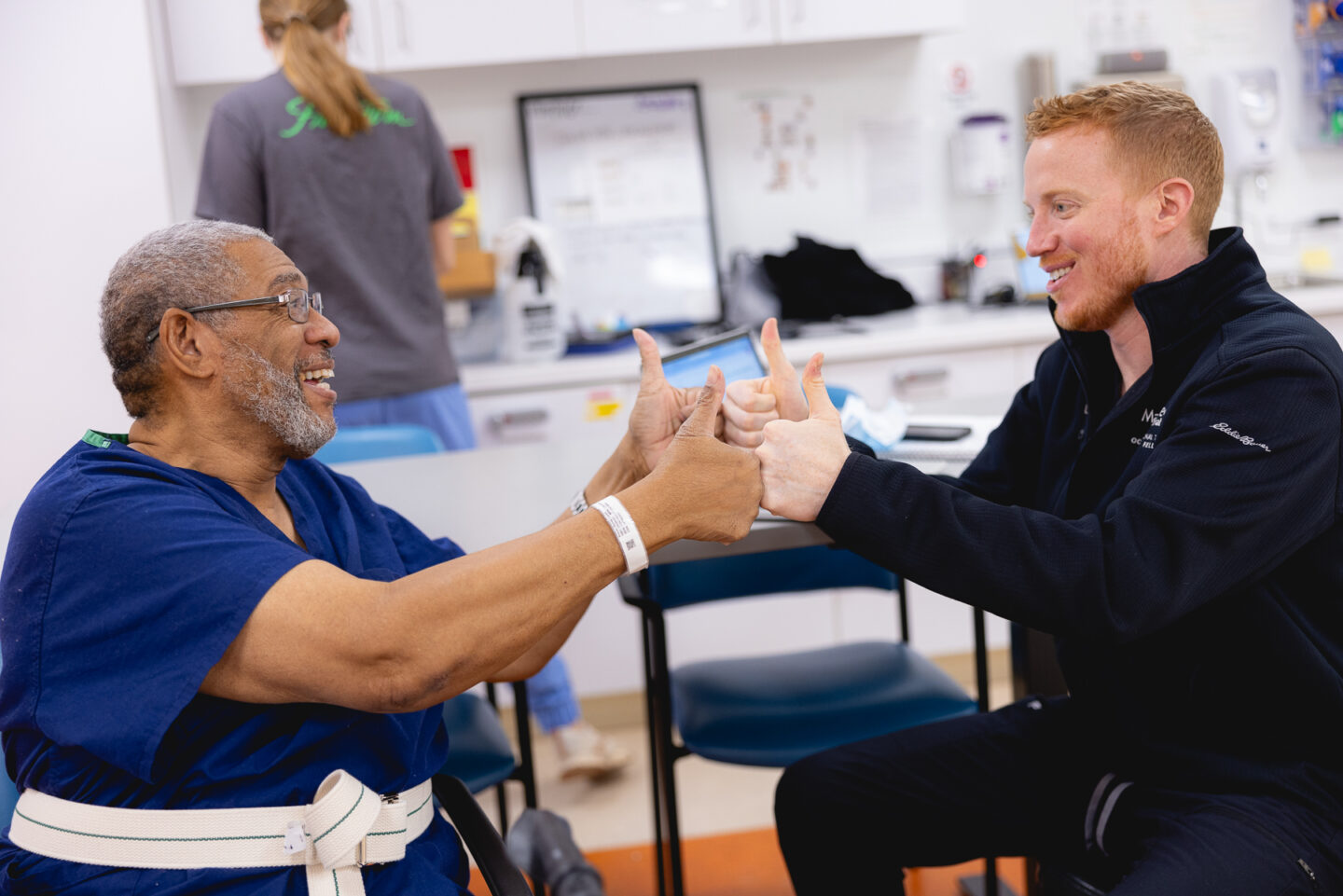 Occupational therapist and patient share a thumbs-up moment during a rehabilitation session focused on improving coordination and confidence.